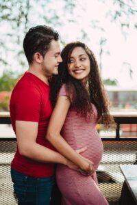 A man hugs his partner's pregnant belly. Intimacy is an important tool for labor.